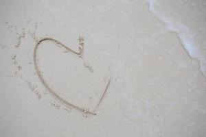 Herzen auf den Sand eines Strandes gezeichnet foto