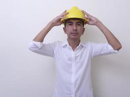 Ingenieur mit gekreuzten Händen mit gelbem Helm auf weißem Hintergrund foto