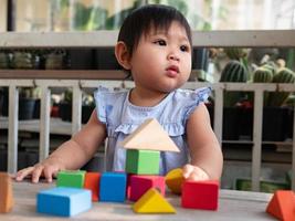 Kleines asiatisches Mädchen, das mit Holzblöcken auf dem Boden spielt foto