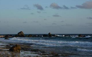Wellen, die kurz nach Sonnenaufgang auf Aruba an Land rollen foto