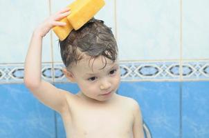 Junge wäscht seinen Kopf mit einem Schwamm