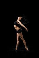 junger Balletttänzer, der auf schwarzem Hintergrund tanzt foto