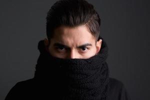 junger Mann mit Schal, der Gesicht bedeckt foto
