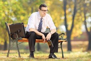 enttäuschter Geschäftsmann, der auf einer Holzbank im Park sitzt foto