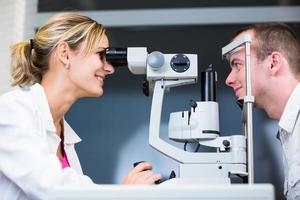 Optometrie-Konzept - hübsche junge Frau, die ihre Augen untersuchen lässt