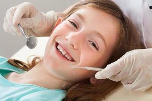 glückliches Mädchen, das Zahnbehandlung unterzieht