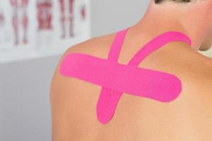 männliche Patienten zurück mit aufgebrachtem rosa Kinesio-Klebeband