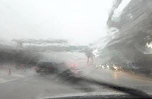 straßenansicht durch autofenster mit starkem regen und sturmschlägen fahren bei regen, verkehrsansicht von der windschutzscheibe des autos bei regen, fahren bei regen foto