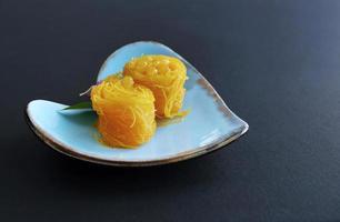 nahaufnahme von fios de ovos im thailändischen stil, gerollter goldener eigelbfaden, traditionelles süßes dessert in blauer herzformplatte, mit kopienraum foto