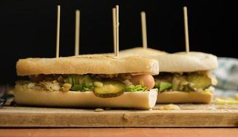 Hot Dogs mit Wurst, Gurken, Salat und Röstzwiebeln auf einem Holzbrett, hausgemacht foto