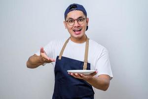 asiatischer barista-mann, der aufgeregten ausdruck zeigt, während er einen leeren teller hält foto