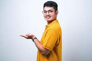 asiatischer mann, der mit offenen handflächen zur seite zeigt und kopienraum zeigt, werbung präsentiert, die aufgeregt und glücklich lächelt foto