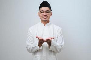 asiatischer muslimischer mann, der seine leere handfläche nach vorne zeigt und etwas hält foto