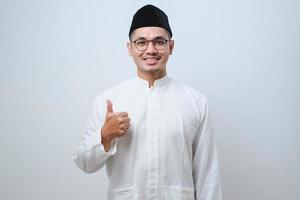 asiatischer muslimischer Mann mit Brille lächelt in die Kamera und zeigt Daumen nach oben foto