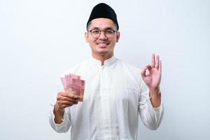 asiatischer muslimischer mann lächelt glücklich, während er papiergeld hält foto