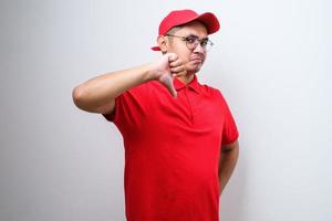 enttäuschter asiatischer lieferbote in rotem t-shirt und kappe drückt abneigung und schlechte einstellung aus foto
