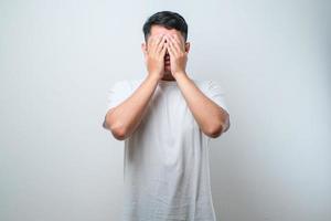 junger gutaussehender asiatischer mann mit lässigem hemd und brille mit traurigem ausdruck, der das gesicht mit den händen bedeckt, während er weint. Depressionskonzept foto