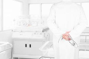 Arzt, der Neugeborenes betrachtet, das im Inkubator im Krankenhaus bedeckt ist foto