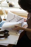 Frau, die zu Hause mit Laptop und Architekturplan arbeitet foto