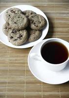 Teepaar und Haferkekse mit Schokolade auf einer Matte. leckeres frühstück mit tee und süßen keksen. foto