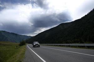 Band der Straße zwischen den Hängen der Berge auf den Weiten des Altai an einem Sommertag foto