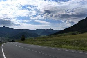 Band der Straße zwischen den Hängen der Berge auf den Weiten des Altai an einem Sommertag foto