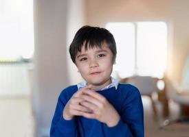 porträt glückliches schulkind mit uniform, das sich morgens zur schule fertig macht, süßer kleiner junge, der mit lächelndem gesicht in die kamera schaut, positives kinderkonzept foto