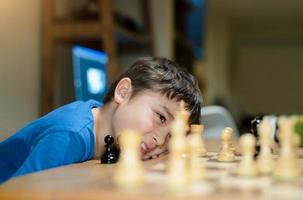 Selektiver Fokus Fröhlicher Junge, der Schachstrategie entwickelt und zu Hause mit den Eltern Brettspiel spielt. aktivität oder hobby für familienkonzept foto