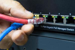 techniker verbindet kabelnetzwerk mit switch-port im serverraum, konzept internet-netzwerkmanagement foto