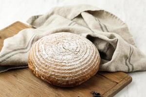 Rundes Sauerteig-Boule-Brot auf Holztablett foto