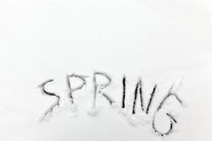 die Worte Frühling auf den Schnee gezeichnet foto