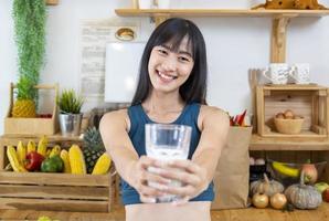 gesunde asiatische frau, die ein glas milch trinkt, während sie sportkleidung für ernährung und proteinergänzung für schwangerschafts- und mutterschaftsleistungskonzept trägt foto