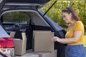 kaukasische reife frau hält pappkarton, um im auto für hausumzugs- und umzugskonzept zu verpacken foto