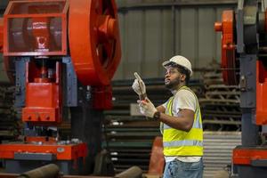 afroamerikanischer industriearbeiter verwendet walkie-talkie, während er in der metallblechfabrik mit verzinktem dach für das konzept der sicherheitsindustrie arbeitet foto