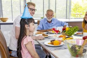 kleine mädchengeburtstagsfeier mit der ganzen familie aus verschiedenen generationen und nachbarn, die sich zum feieressen zusammenschließen foto