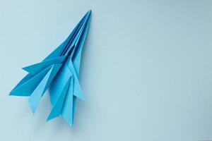 Origami-Flugzeug aus blauem Papier auf hellblauem Hintergrund. Hintergrund mit Platz für Text foto