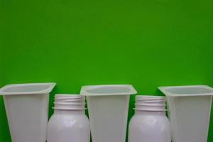 weiße Plastikflaschen auf grünem Hintergrund mit Platz für Ihr Design. Ansicht von oben foto