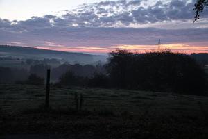 aufgehende Sonne auf nebliger Wiese am Morgen im Saarland foto