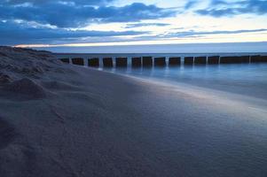 Sonnenuntergang am Strand der Ostsee. Buhnen reichen ins Meer. blaue Stunde foto