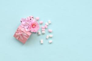 geblümte rosa geschenkbox mit marshmallows auf blauem hintergrund bestreut foto