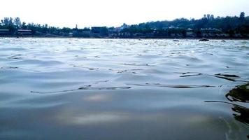 wasseroberfläche mit wellen und sonnenstrahlenreflexionen im ganga-fluss in rishikesh foto