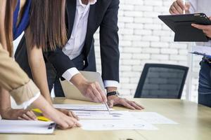 geschäftsteam applaudiert seinem führer nach erfolg im büro und diskutiert dokumente und ideenbericht bei treffen, diskussionsstrategie-gruppenarbeitskonzept foto