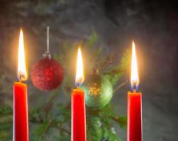 Weihnachtsrote Kerzen brennen auf dem Hintergrund von Tannenzweigen. Weihnachtsdekoration. Atmosphäre des neuen Jahres foto