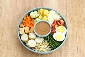 gado gado, indonesischer traditioneller gemüsesalat mit erdnusssoße, reiskuchen, tofu und ei foto