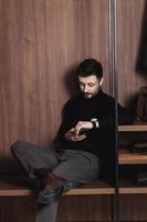 Eleganter Mann sitzt mit einem Telefon foto