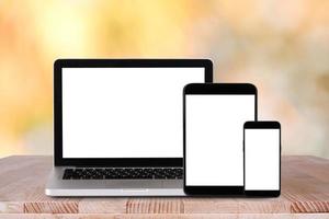 Vorderansicht des Laptops, Tablet-PC, Smartphone befindet sich auf dem Arbeitstisch mit orangefarbenem Bokeh-Hintergrund foto