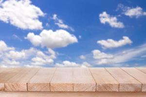 braune Holztischplatte auf bokeh abstraktem blauem Himmelshintergrund - kann für die Montage oder Präsentation Ihrer Produkte verwendet werden foto