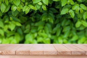 braune Holztischplatte auf bokeh abstraktem grünem Naturhintergrund - kann für die Montage oder Präsentation Ihrer Produkte verwendet werden