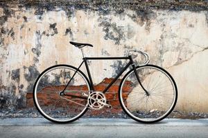 Stadtfahrrad Festrad und rissiger Beton alter Mauerhintergrund foto