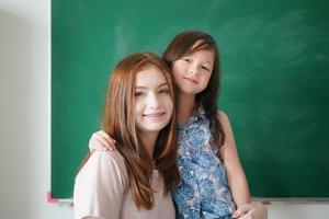 glückliche kleine Mädchen gegen Tafel mit zurück zur Schule foto